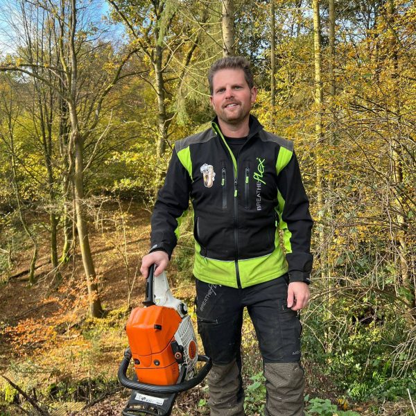 Stefan Thurau im Einsatz: Nachhaltige Forstwirtschaft und kreativer Galabau Hand in Hand. Stefan Thurau in voller Montur im Wald – Der Experte für nachhaltige Forstwirtschaft und Galabau, mit Motorsäge in der Hand.